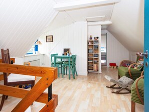 A cozy attic room with a wooden bed, a dining table with chairs, a bookshelf, and a rocking chair. - 6 Person Holiday Home in Orsted (Ørsted)