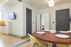 Un comedor moderno con una mesa redonda de madera, sillas amarillas y un televisor de pantalla plana montado en la pared.