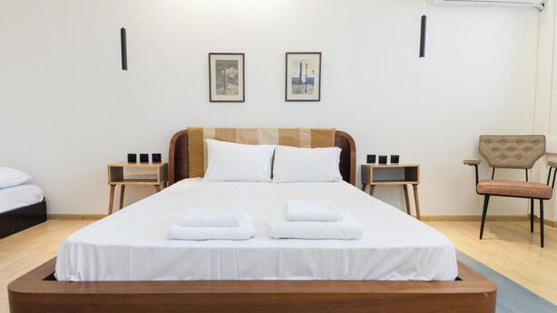 Een moderne hotelkamer met een groot bed, twee nachtkastjes, een stoel en een kunstwerk in een lijst aan de muur.