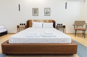 Una habitación de hotel moderna con una cama grande, dos mesitas de noche, una silla y cuadros en la pared.