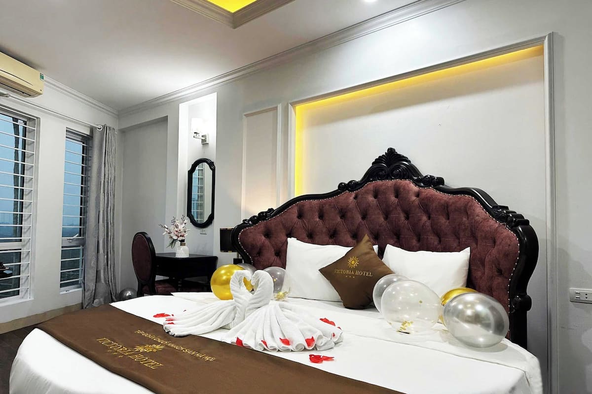 A hotel room with a large bed, a mirror, and a desk with a vase of flowers.