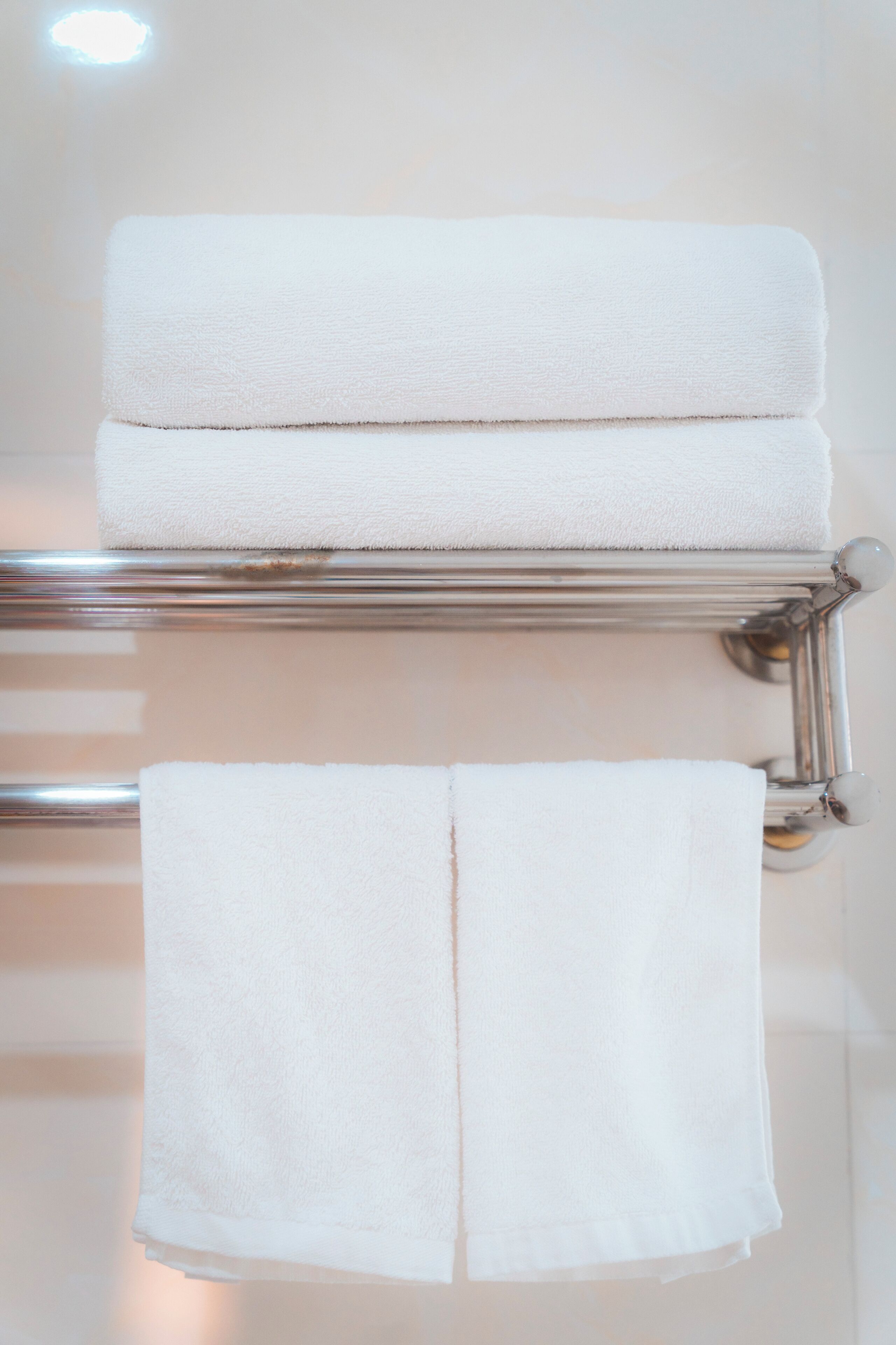 A bathroom with a towel rack holding two folded towels.