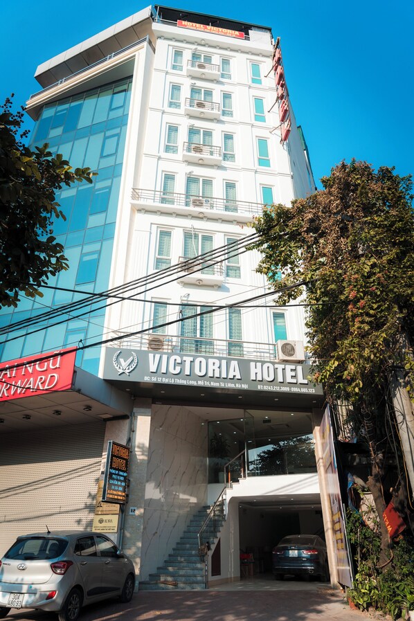 A hotel with a modern facade, a visible entrance, and a staircase leading to the parking area. - Victoria Hotel Me Tri (Hanoi)