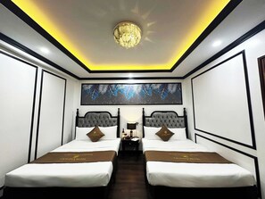 A hotel room with two beds, a chandelier, a large leaf-patterned artwork, and a brown bedspread. - Victoria Hotel Me Tri (Hanoi)