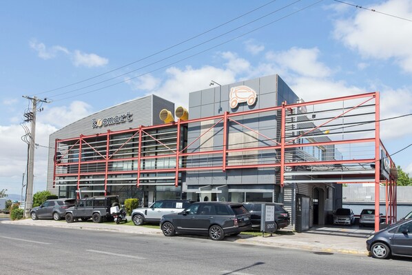 A modern building with a prominent 'KOSMART' sign, featuring a car icon and a red metal structure.