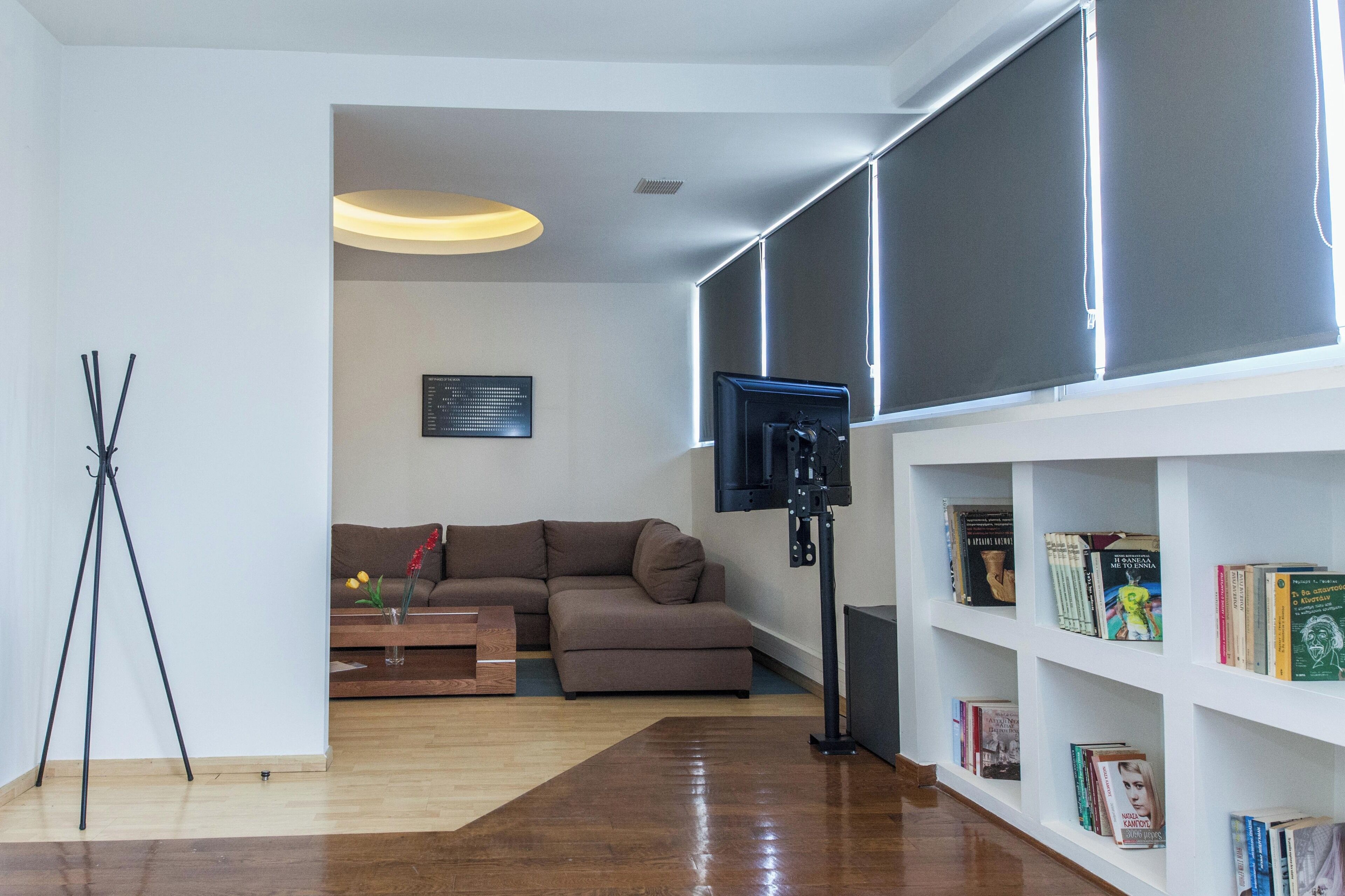 Ein modernes Wohnzimmer mit einem braunen Sofa, einem Couchtisch und einer Bücherwand voller Bücher.