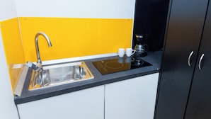 Una cocina compacta con un lavamanos, una cafetera y una pequeña encimera.