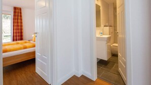A bedroom with a bed, a bathroom with a sink and toilet, and a view of the outdoors. - Pleasant Apartment in Suddorf (Nebel)
