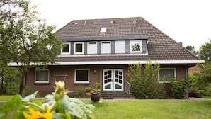 A two-story house with a brick facade, a tiled roof, and a front porch. - Pleasant Apartment in Suddorf (Nebel)