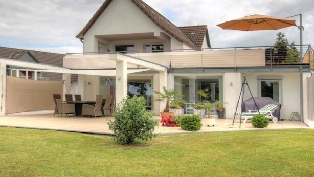 A modern two-story house with a covered patio, outdoor seating, and a barbecue area. - Holiday Apartment Schliekieker (Kappeln)