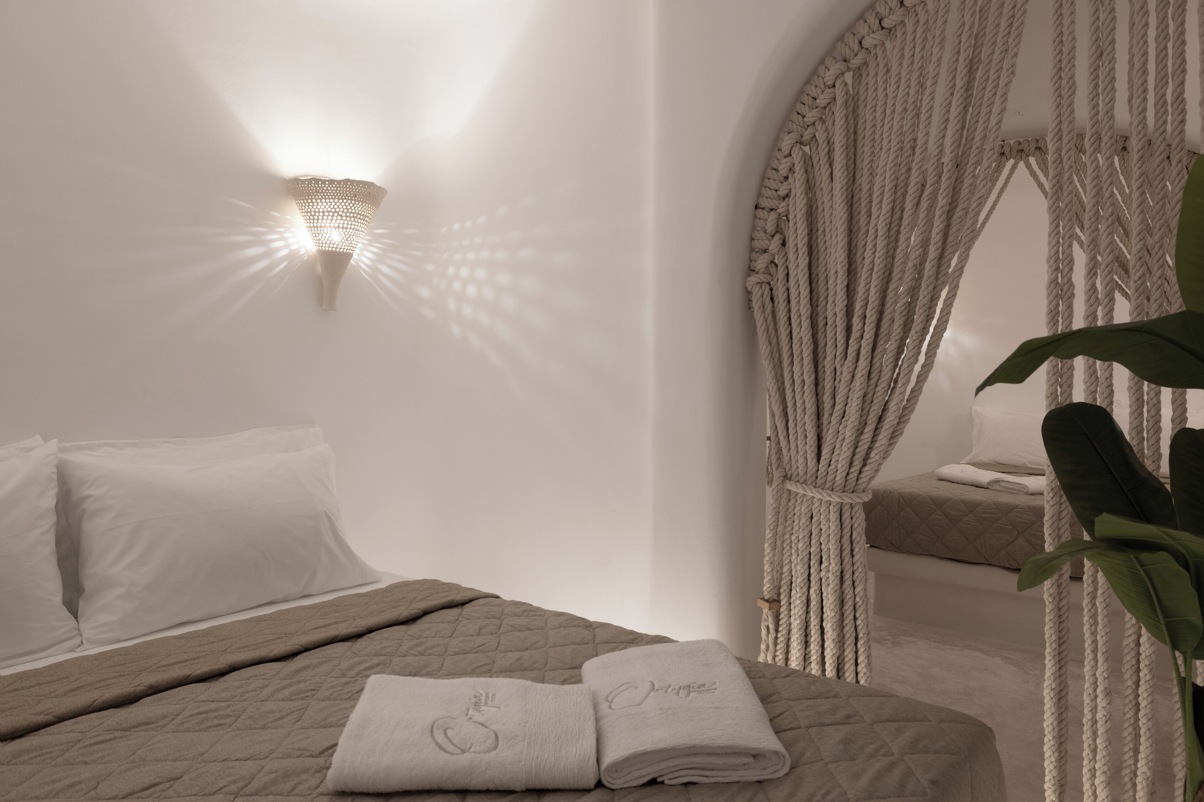 Un dormitorio con cama, luz empotrada en la pared y cortina de cuerda.
