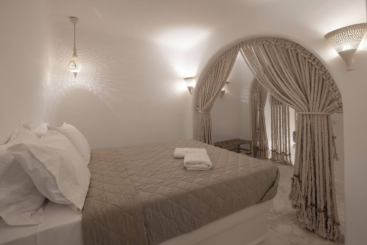 A bedroom with a bed, a hanging light fixture, and a wall-mounted light.