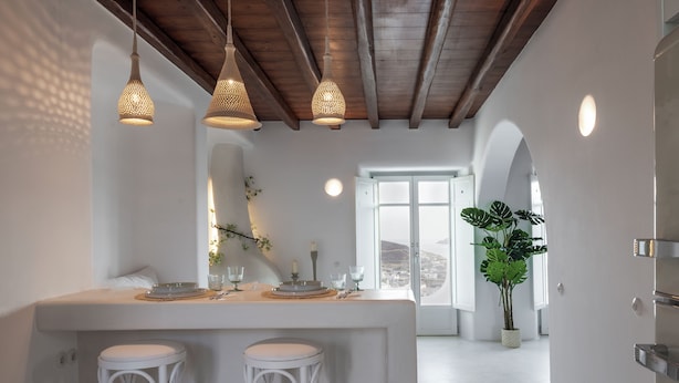 Una cocina moderna con una isla central, luces colgantes y una planta grande en maceta.