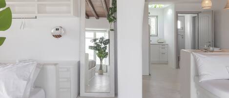 Una habitación moderna y minimalista con mobiliario blanco, techo de madera y un espejo grande.