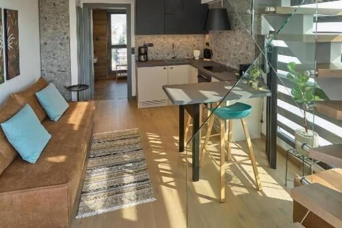 A modern loft-style apartment with a spacious living area, a kitchen, and a glass staircase.