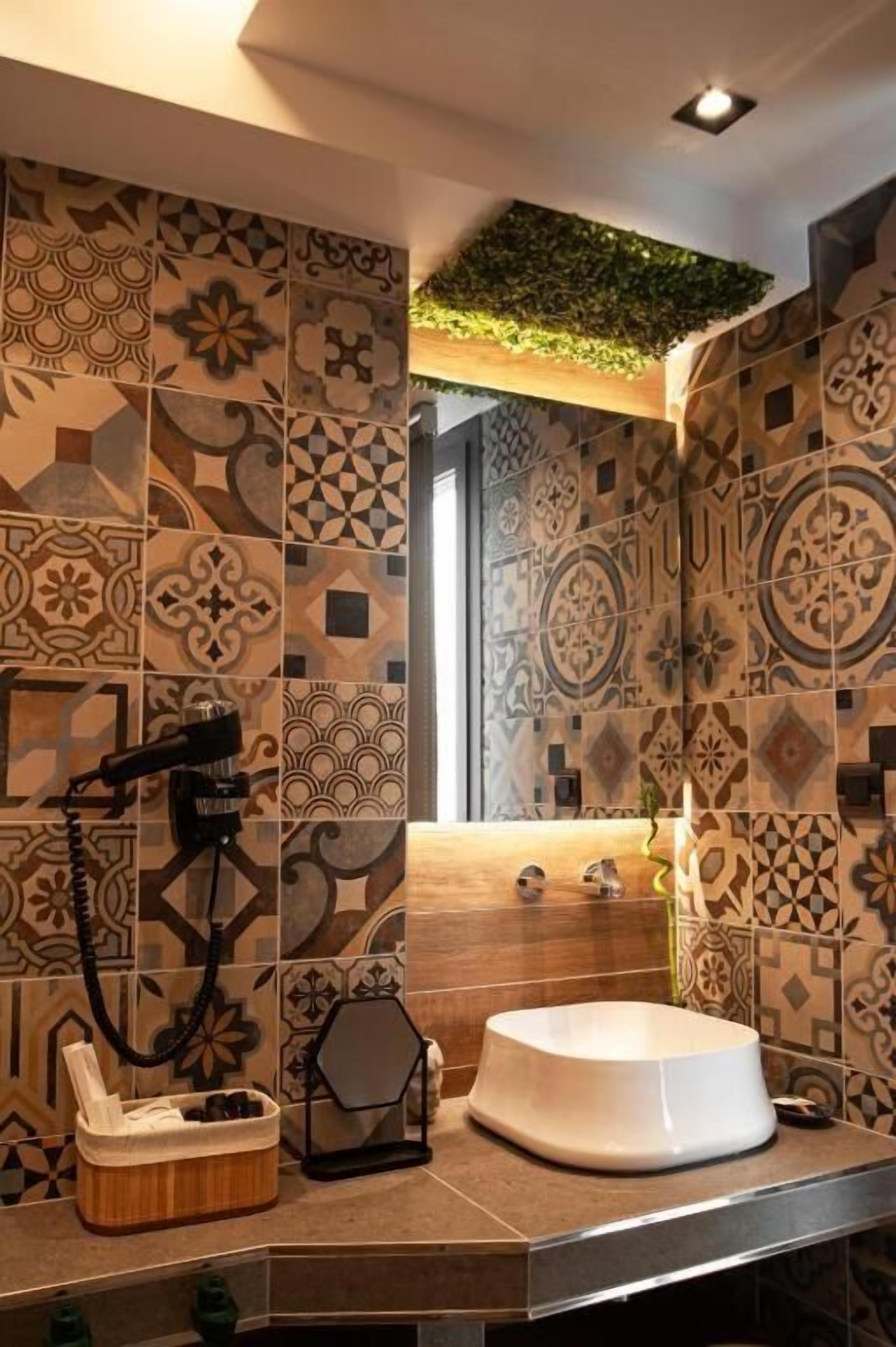 A bathroom with patterned tiles, a white basin, and a hairdryer on the counter.