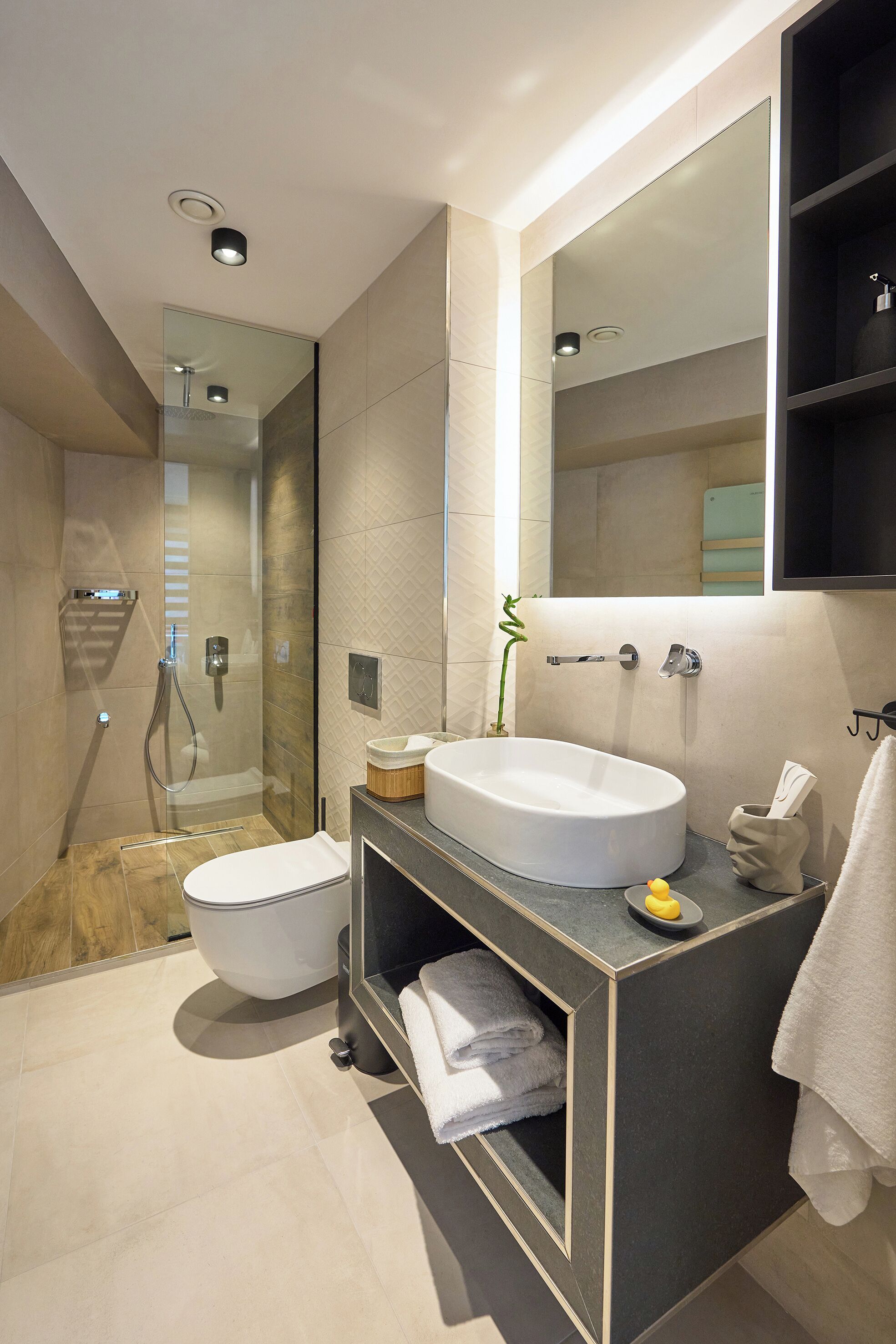 Une salle de bain moderne avec une douche à parois de verre, des toilettes blanches et un meuble-lavabo avec un lavabo et un miroir.