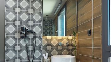 Un baño moderno con un salpicadero de azulejos geométricos, un lavabo blanco y un jardín vertical integrado.