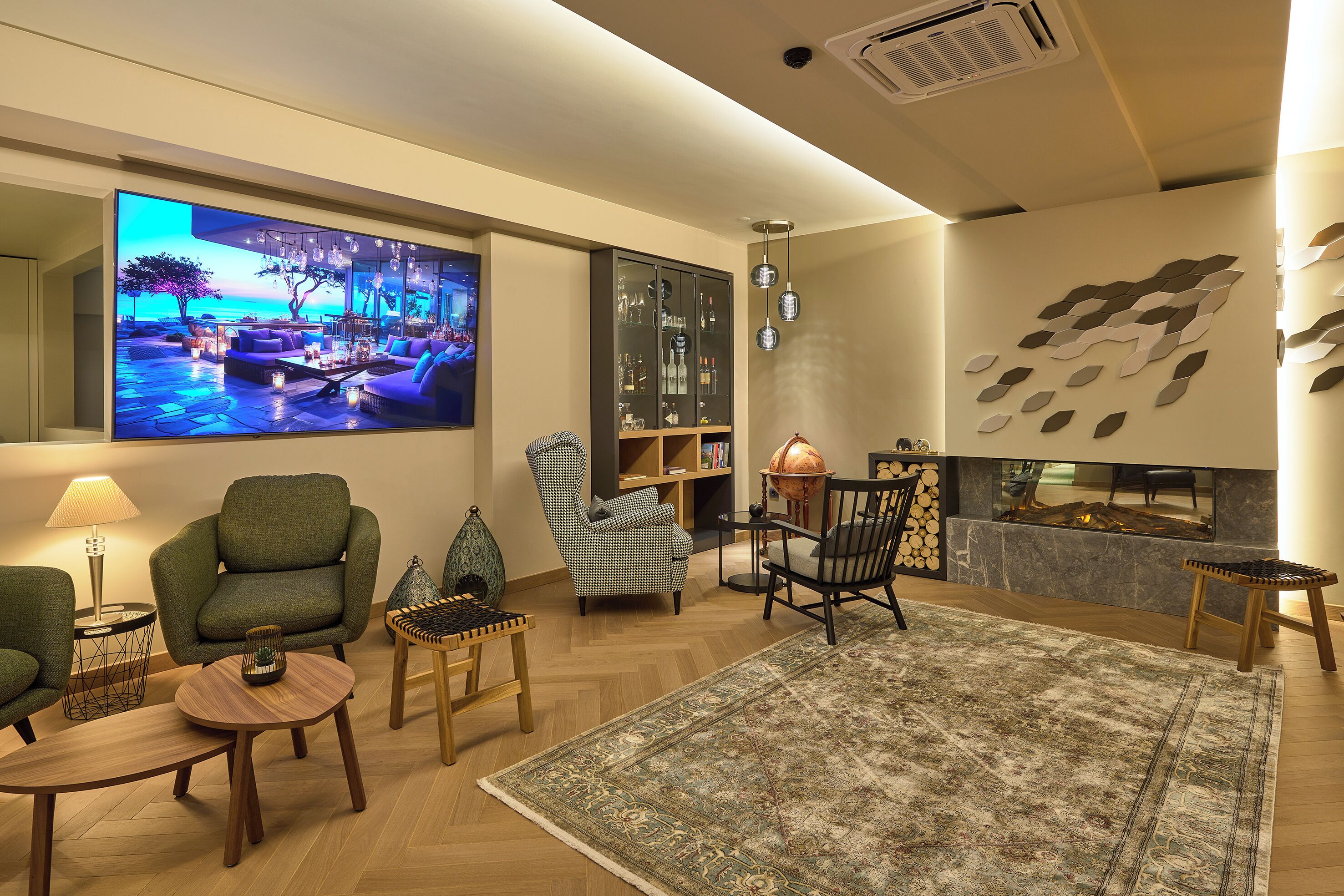 A modern living room with a large flat-screen TV, comfortable seating, a fireplace, and a bookshelf.
