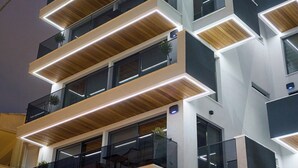 A modern multi-story building with illuminated horizontal lines and balconies. - SIGMA Suites Hotel (Neapoli-Sykies)