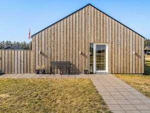 Un bâtiment en bois avec une grande porte et un banc à l’extérieur.