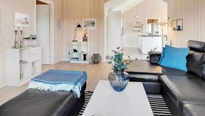 Un salon moderne avec un canapé en cuir noir, une table basse blanche et un vase bleu.