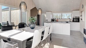Une cuisine moderne avec des meubles blancs, un îlot central et des luminaires suspendus.