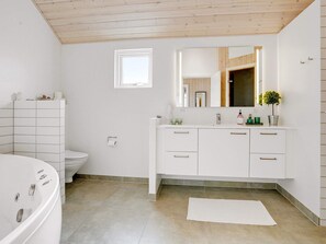 Une salle de bain moderne avec une baignoire blanche, des toilettes et un meuble-lavabo avec un miroir.