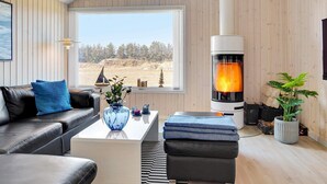 Un salon chaleureux avec une cheminée, un canapé, une table basse et une vue sur l’extérieur.