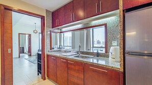 Una cocina moderna con armarios de madera, un refrigerador de acero inoxidable y un amplio ventanal con vistas a la ciudad.