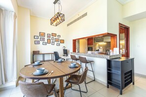 A dining area with a round table, chairs, and a kitchen counter. - SuperHost - Chic Downtown Living 1BR in Dubai's South Ridge 5 (Dubai)