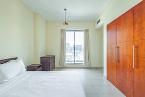 A hotel room with a large bed, a wardrobe, a dresser, and a window with curtains. - SuperHost - Chic Downtown Living 1BR in Dubai's South Ridge 5 (Dubai)