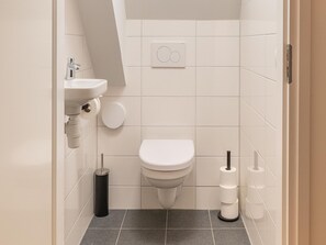 A small, modern bathroom with a toilet, sink, and toilet paper holder. - Renovated Apartment in the Center of Sneek (Sneek)