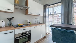 Eine moderne Küche mit weißen Schränken, einem eingebauten Backofen, einer Edelstahl-Dunstabzugshaube und einem Fenster mit Jalousien.