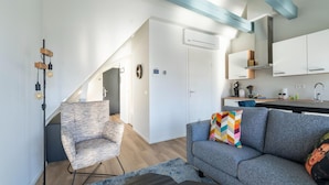 Eine moderne Wohnung mit Wohnzimmer, Küchenzeile und einer Treppe, die zu einer oberen Etage führt.