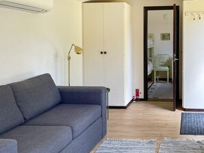 A room with a grey sofa, a wardrobe, a lamp, and a chair. - 4 Person Holiday Home in Beddingestrand (Trelleborg)