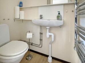 A bathroom with a toilet, a sink, and a toilet paper holder. - 4 Person Holiday Home in Beddingestrand-by Traum (Trelleborg)