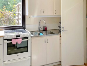 Une cuisine équipée d’une cuisinière, d’un four, d’un évier et de placards.