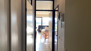 Un pasillo que conduce a una sala de estar con sofá y mesa, un refrigerador y una puerta con picaporte.