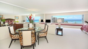 A modern living room with a glass dining table, patterned chairs, a sofa, and a large window with a view of the ocean. - Breathtaking Ocean Views from Quiet Beachfront Condo! Free Parking & Wi-Fi! (Honolulu)