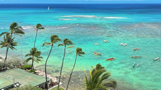 A beach with clear turquoise water, palm trees, and several boats anchored nearby. - Breathtaking Ocean Views from Quiet Beachfront Condo! Free Parking & Wi-Fi! (Honolulu)