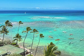 A beach with clear turquoise water, palm trees, and several boats anchored nearby. - Breathtaking Ocean Views from Quiet Beachfront Condo! Free Parking & Wi-Fi! (Honolulu)