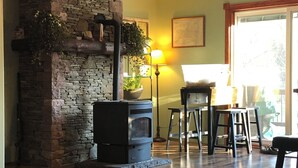 Una sala de estar con chimenea de piedra, suelo de madera y un ventanal grande.