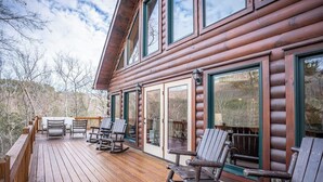 Eine Holzhütte mit einer Veranda, Schaukelstühlen und großen Fenstern.