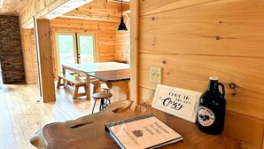 Ein Holzinnenraum mit Tisch, Stühlen, einer Bank, einer Flasche und einem Willkommensschild.