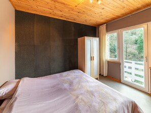 A bedroom with a bed, a wardrobe, and a window with a view of greenery. - Magnificent Holiday Home With hot Tubs (Esneux)