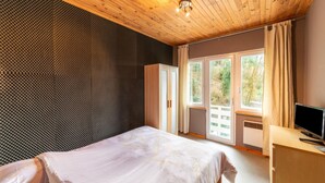 Un dormitorio con cama, escritorio, televisión y ventana con cortinas.