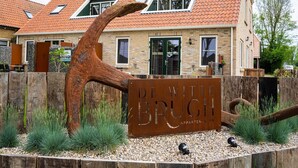 A building with a sign reading "De With Bruch Appartements" surrounded by a wooden fence and greenery. - Luxury new Apartment on Ameland (Buren)
