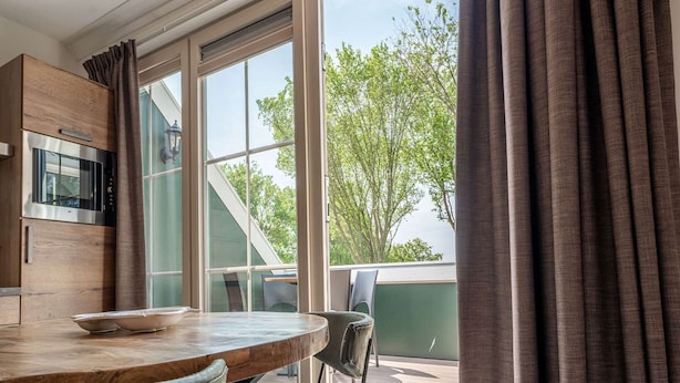 A modern kitchen with a wooden countertop and a dining area with a table and chairs. - Luxury new Apartment on Ameland (Buren)