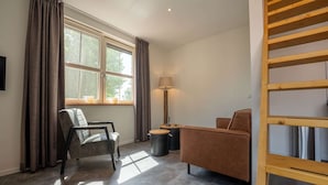 A modern room with a sofa, a chair, a lamp, and a window with curtains. - Luxury new Apartment on Ameland (Buren)